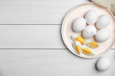 Plate with hard boiled eggs on white wooden table, flat lay. Space for text