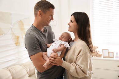 Photo of Happy couple holding their sleeping baby at home