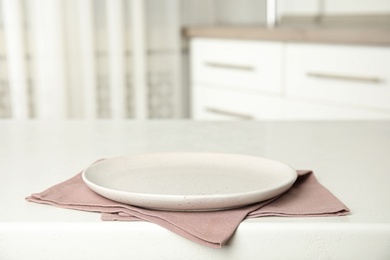 Photo of Empty plate and napkin on white table indoors