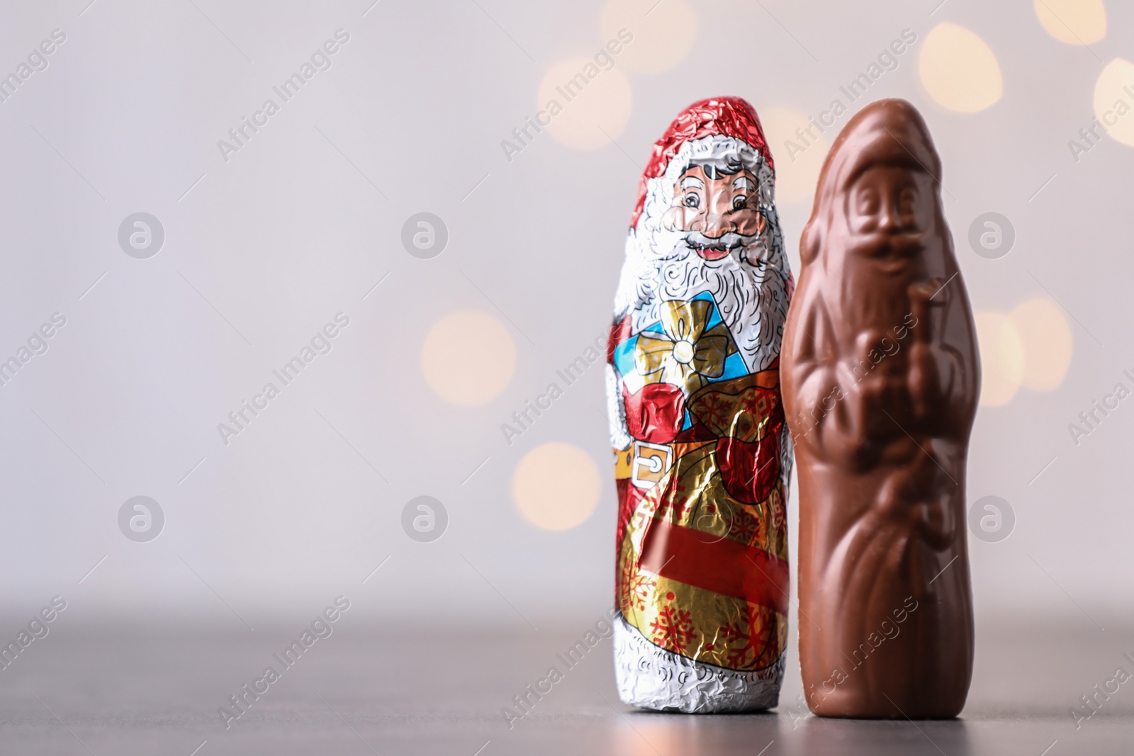 Photo of Chocolate Santa Claus candies on light background, space for text