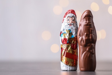 Photo of Chocolate Santa Claus candies on light background, space for text