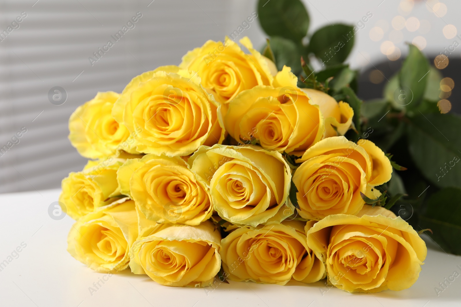 Photo of Beautiful bouquet of yellow roses on white table indoors, closeup