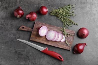 Photo of Wooden board with sliced red onion on table, top view