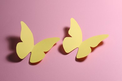 Photo of Two yellow paper butterflies on pink background