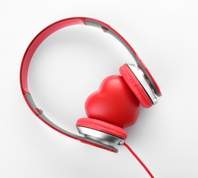 Photo of Headphones and red heart on white background, top view