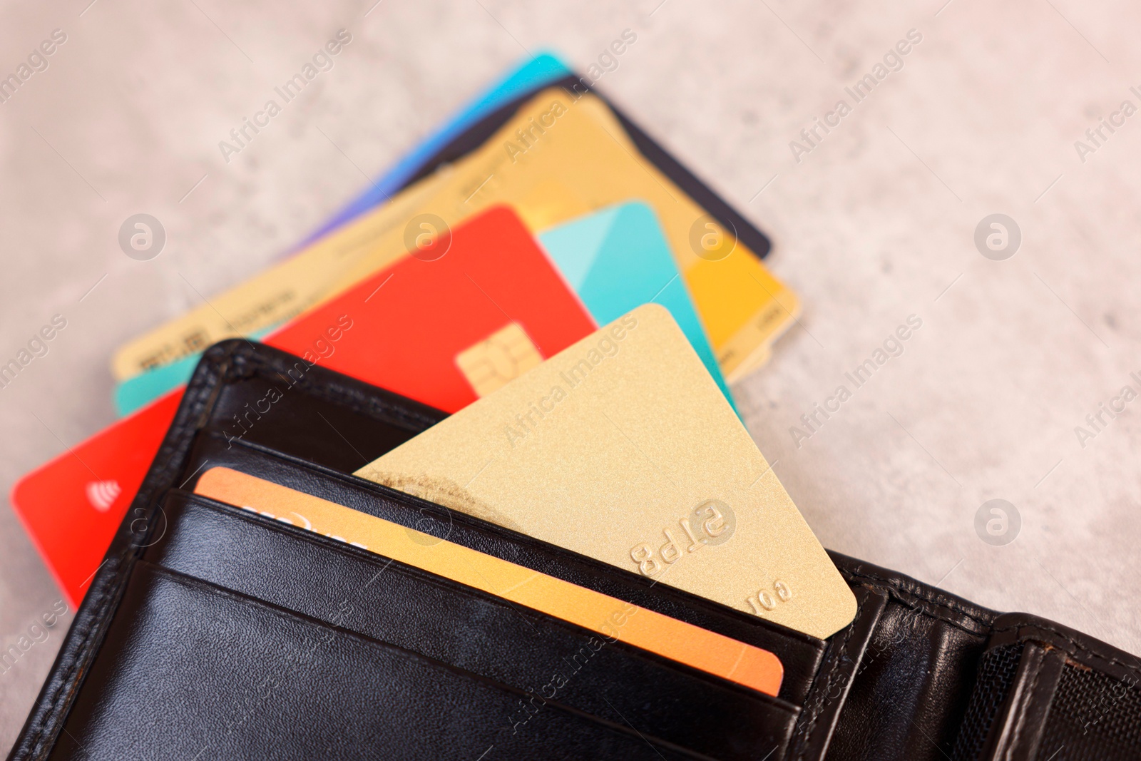 Photo of Many different credit cards and leather wallet on grey table, closeup