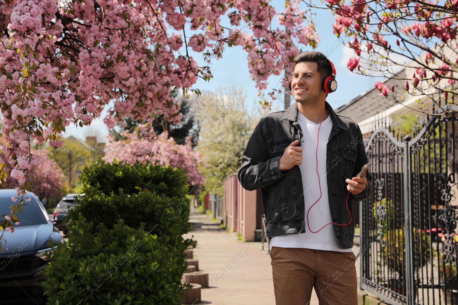 Photo of Happy man with smartphone listening to audiobook outdoors on spring day