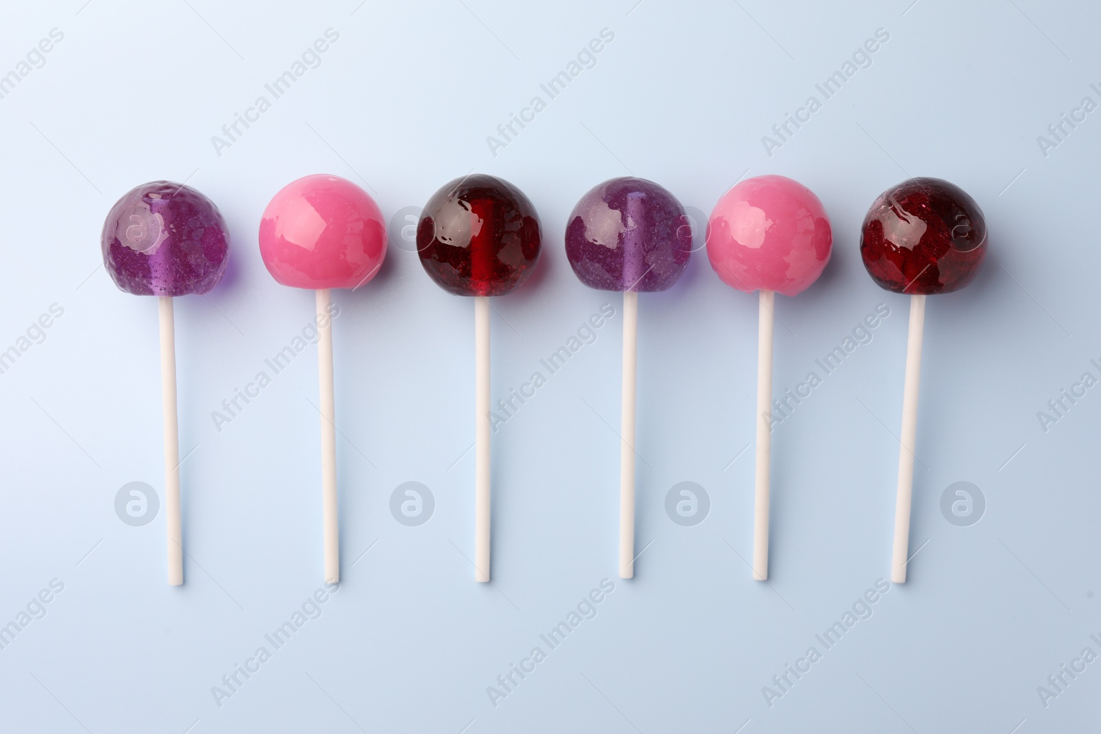 Photo of Tasty lollipops on light blue background, flat lay