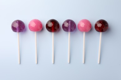 Photo of Tasty lollipops on light blue background, flat lay