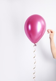 Photo of Woman piercing balloon with needle on white background, closeup