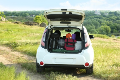 Photo of Car with camping equipment in trunk on green field