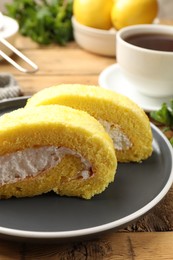 Delicious cake roll with cream filling on wooden table, closeup