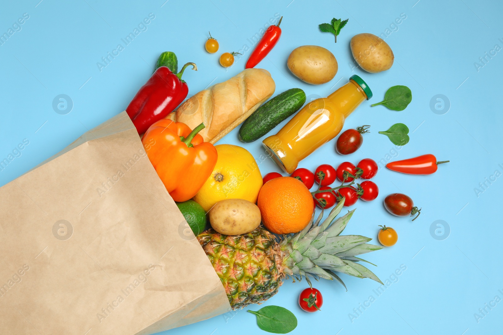 Photo of Shopping paper bag with different groceries on light blue background, flat lay