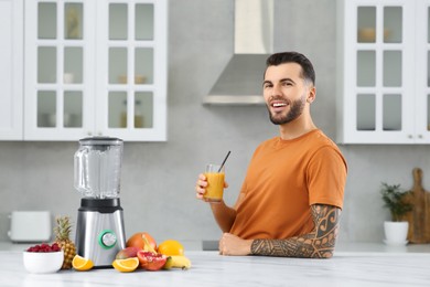 Photo of Handsome man with delicious smoothie at white marble table in kitchen