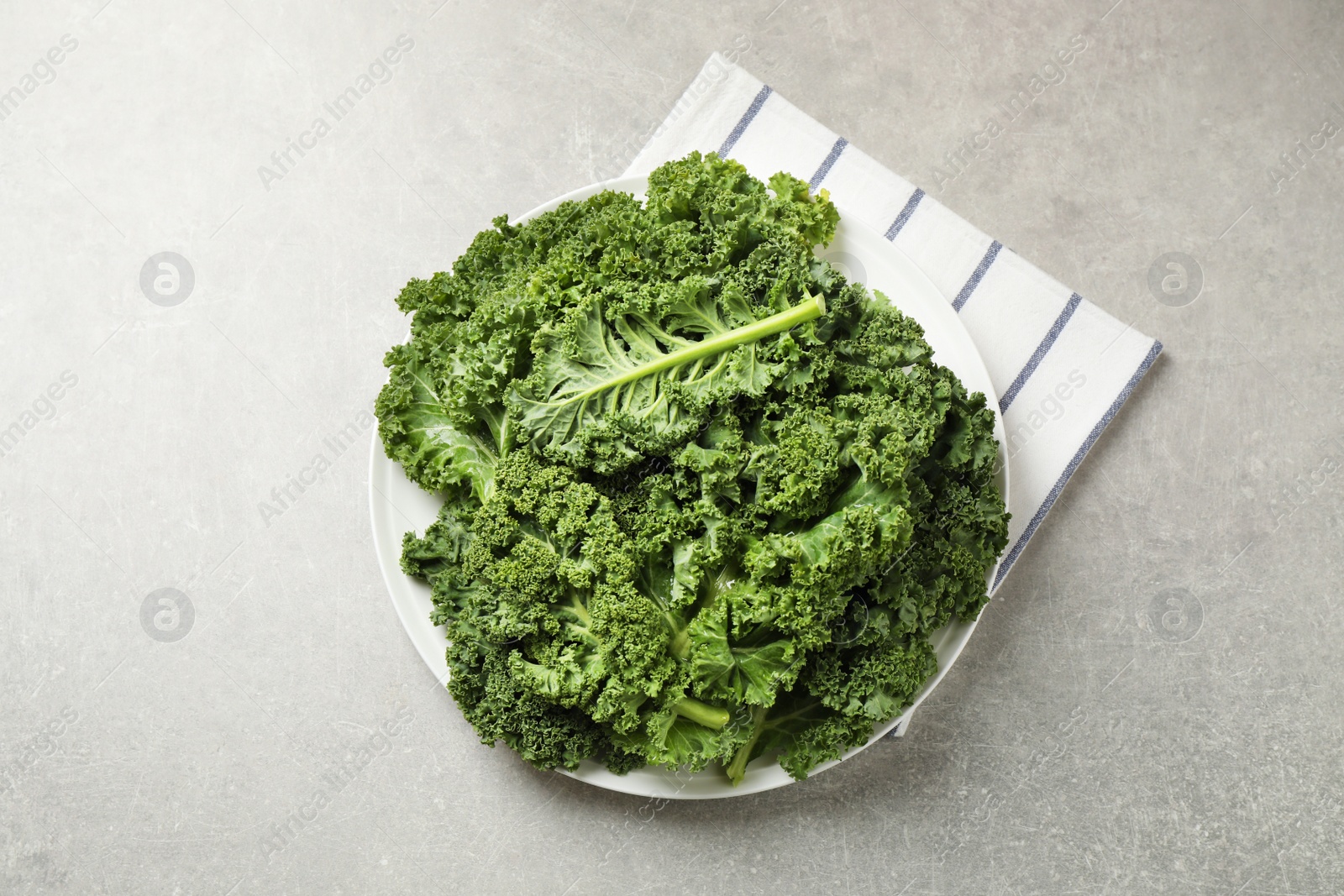 Photo of Fresh kale leaves on grey table, flat lay