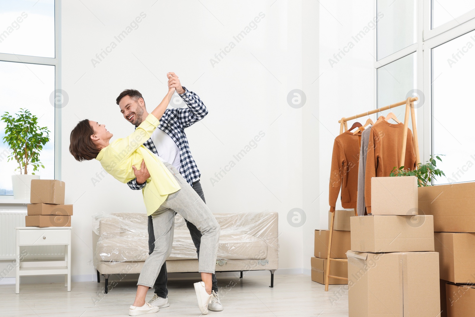 Photo of Happy couple dancing in new apartment. Moving day