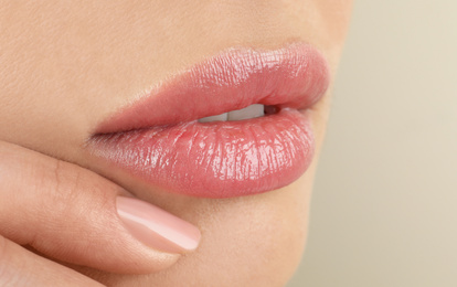 Woman with beautiful full lips on beige background, closeup
