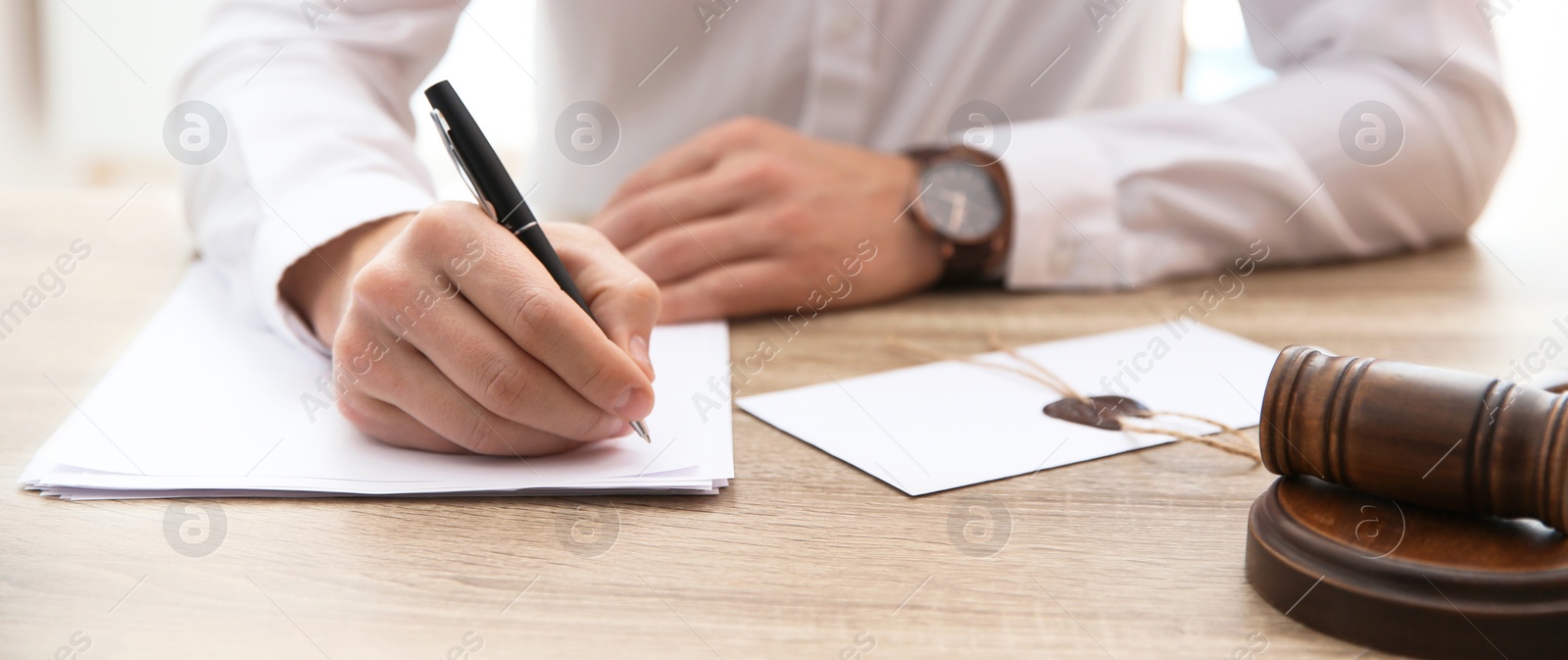 Image of Male notary working with documents and gavel on table in office, closeup. Banner design