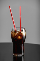 Photo of Glass of cola with ice on table against grey background