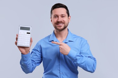 Photo of Happy accountant showing calculator on light grey background