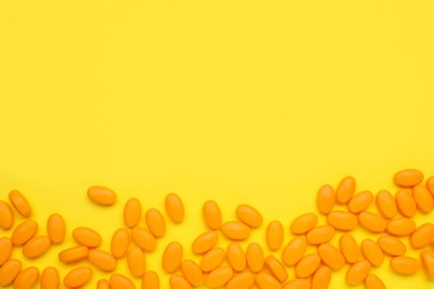Many tasty dragee candies on yellow background, flat lay. Space for text