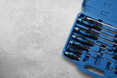 Photo of Set of screwdrivers in open toolbox on grey textured table, top view. Space for text