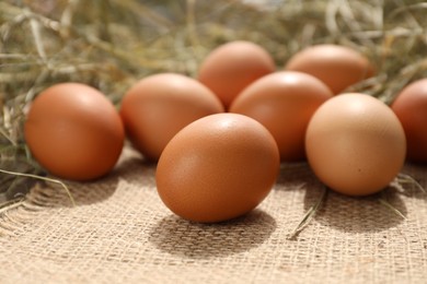 Photo of Fresh chicken eggs on burlap fabric, closeup