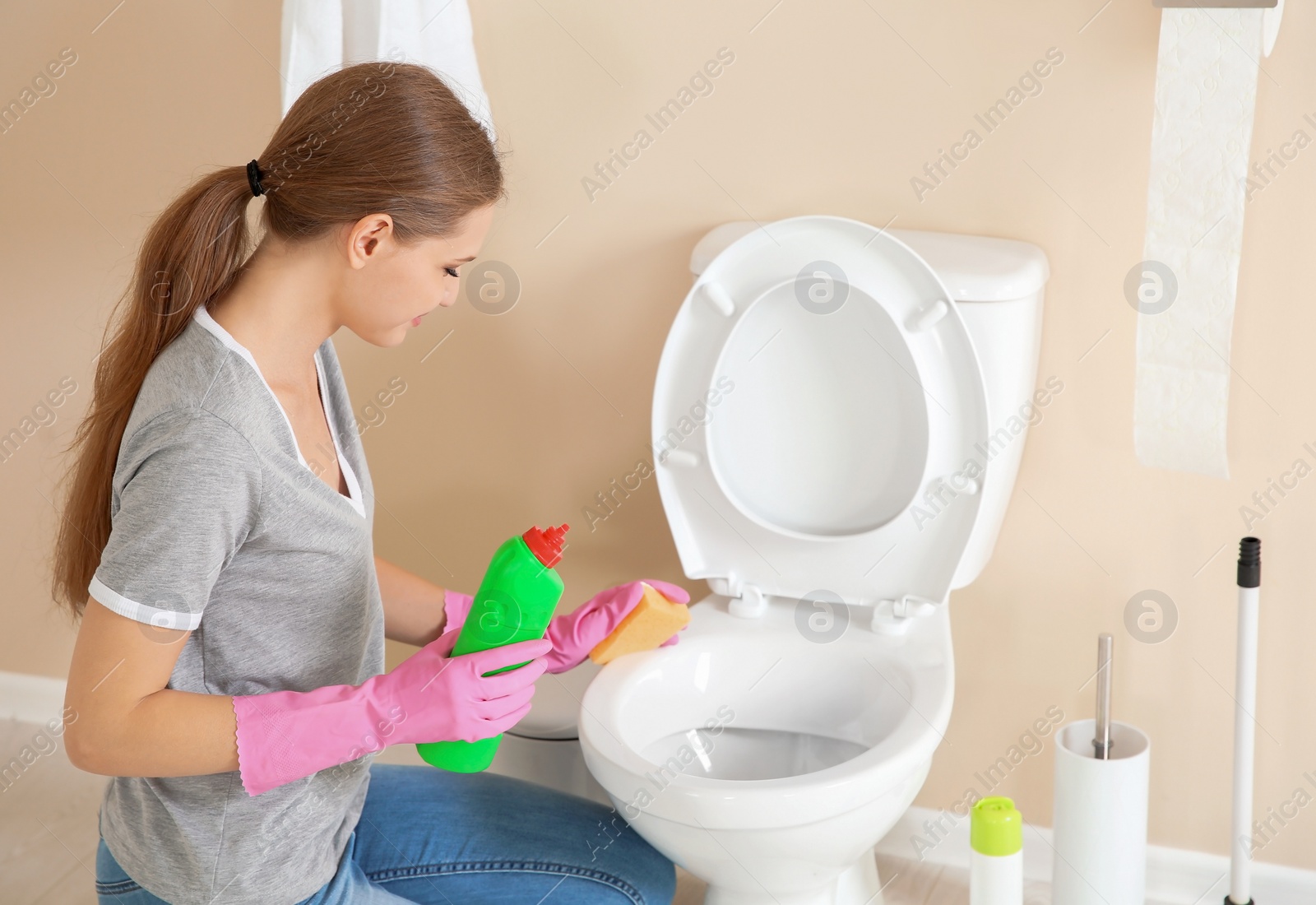 Photo of Woman cleaning toilet bowl in bathroom