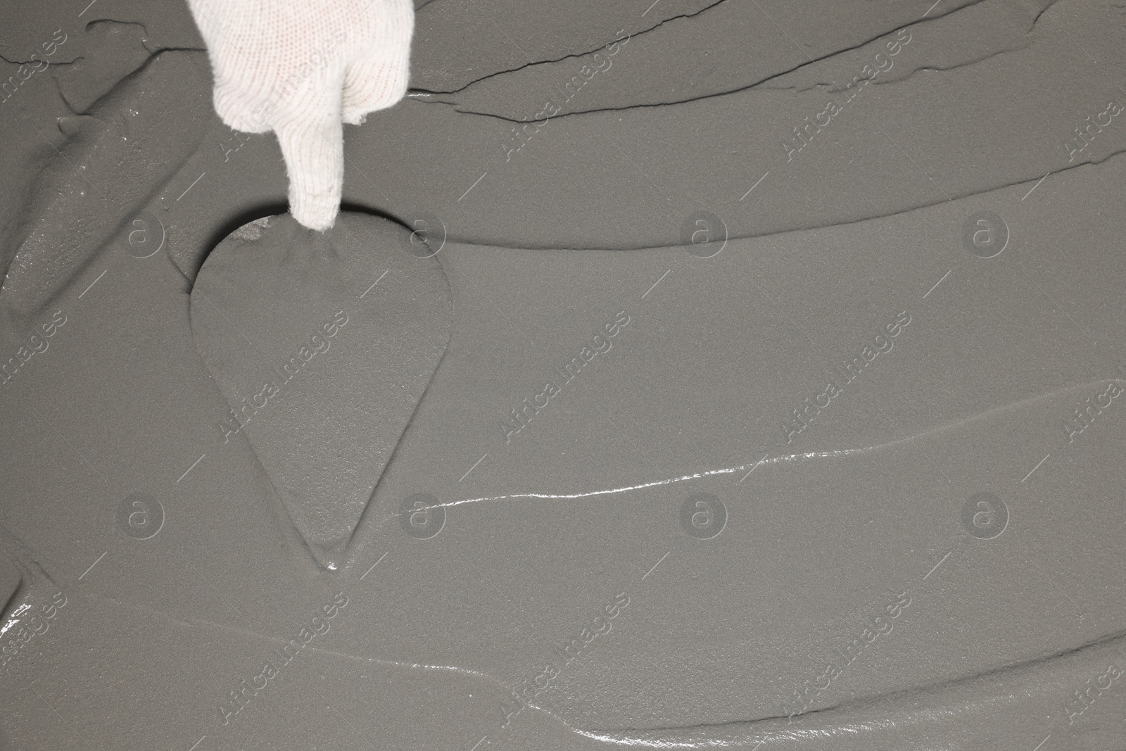 Photo of Worker spreading wet concrete with trowel, closeup. Space for text