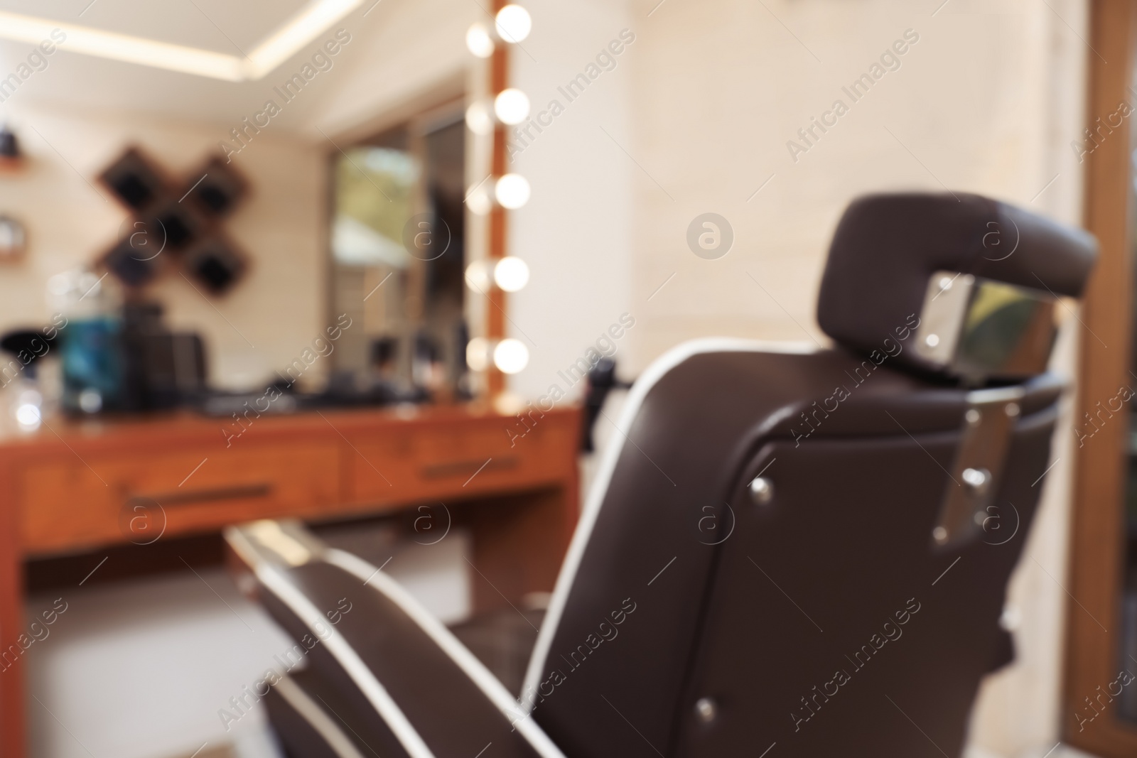 Photo of Blurred view of stylish hairdresser's workplace with professional armchair in barbershop