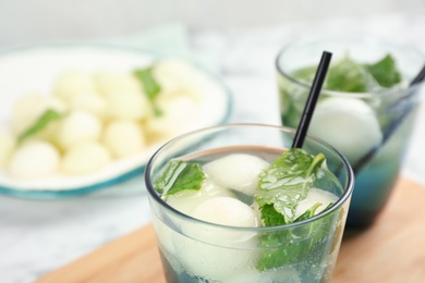 Photo of Glass with tasty melon ball drink on table, closeup