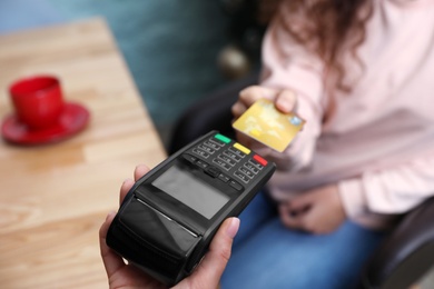 Photo of Client using credit card machine for non cash payment indoors, closeup