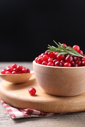 Photo of Fresh ripe cranberries and rosemary on wooden table