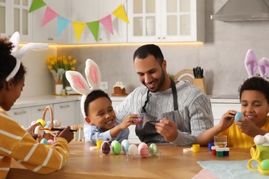 Happy African American family painting Easter eggs at table in kitchen