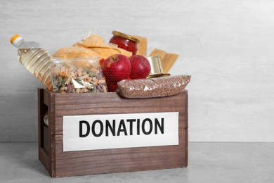 Photo of Donation box with food on table against light background