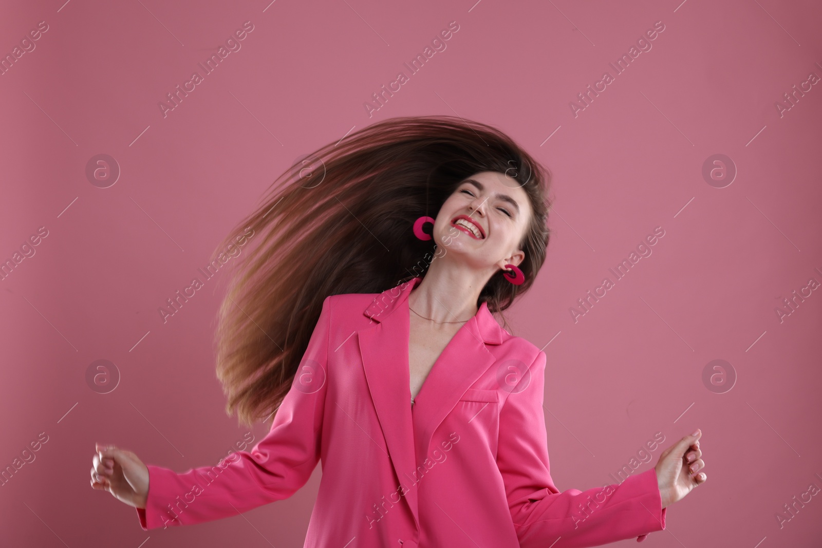 Photo of Beautiful young woman in pink clothes having fun on color background