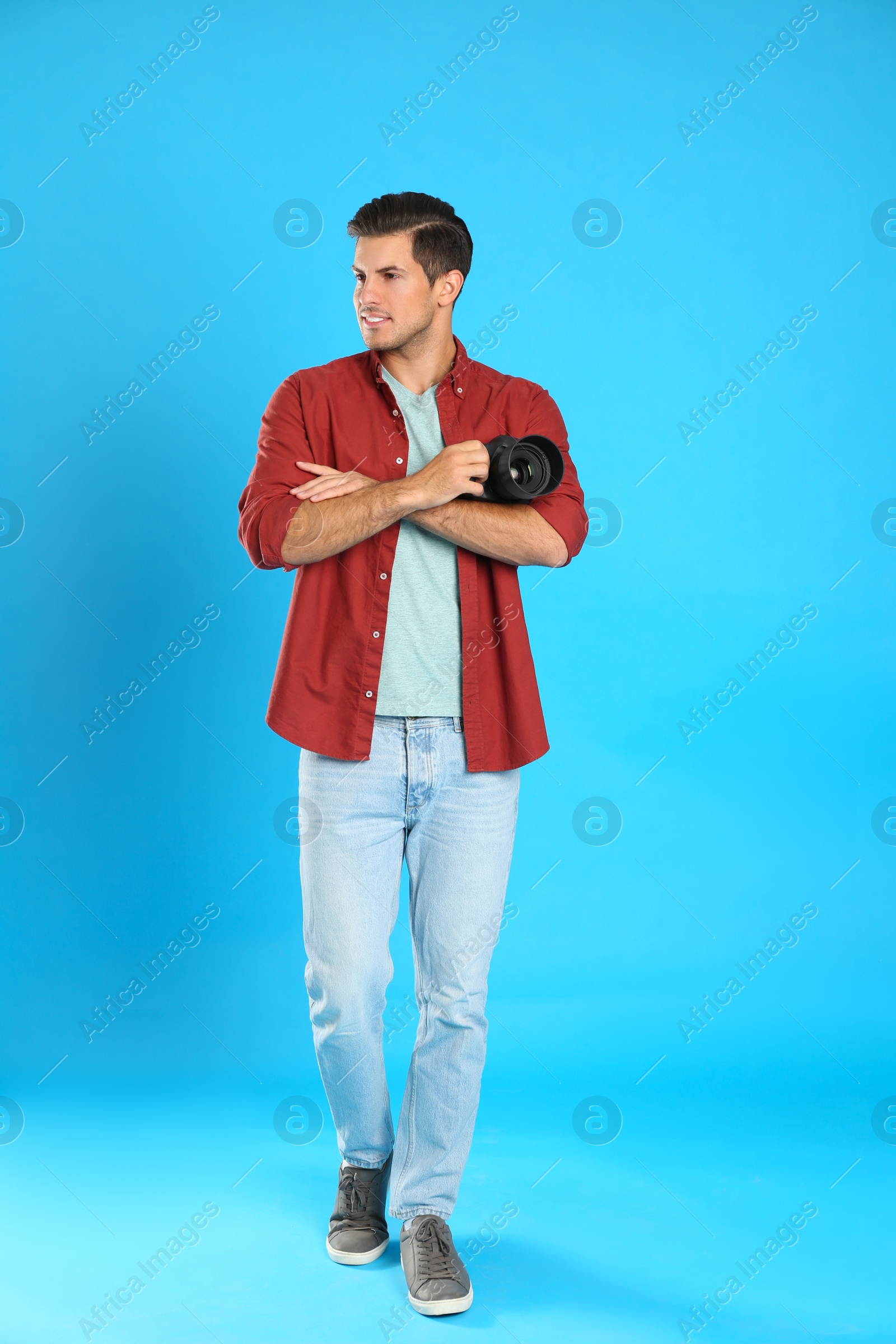 Photo of Professional photographer working on light blue background in studio