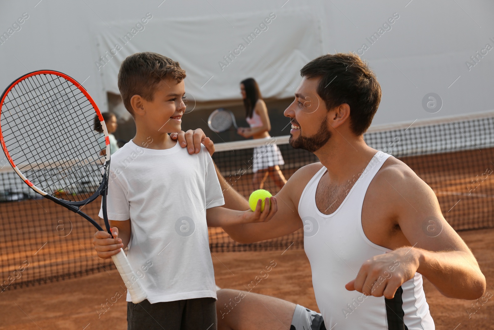 Photo of Father with his son on tennis court