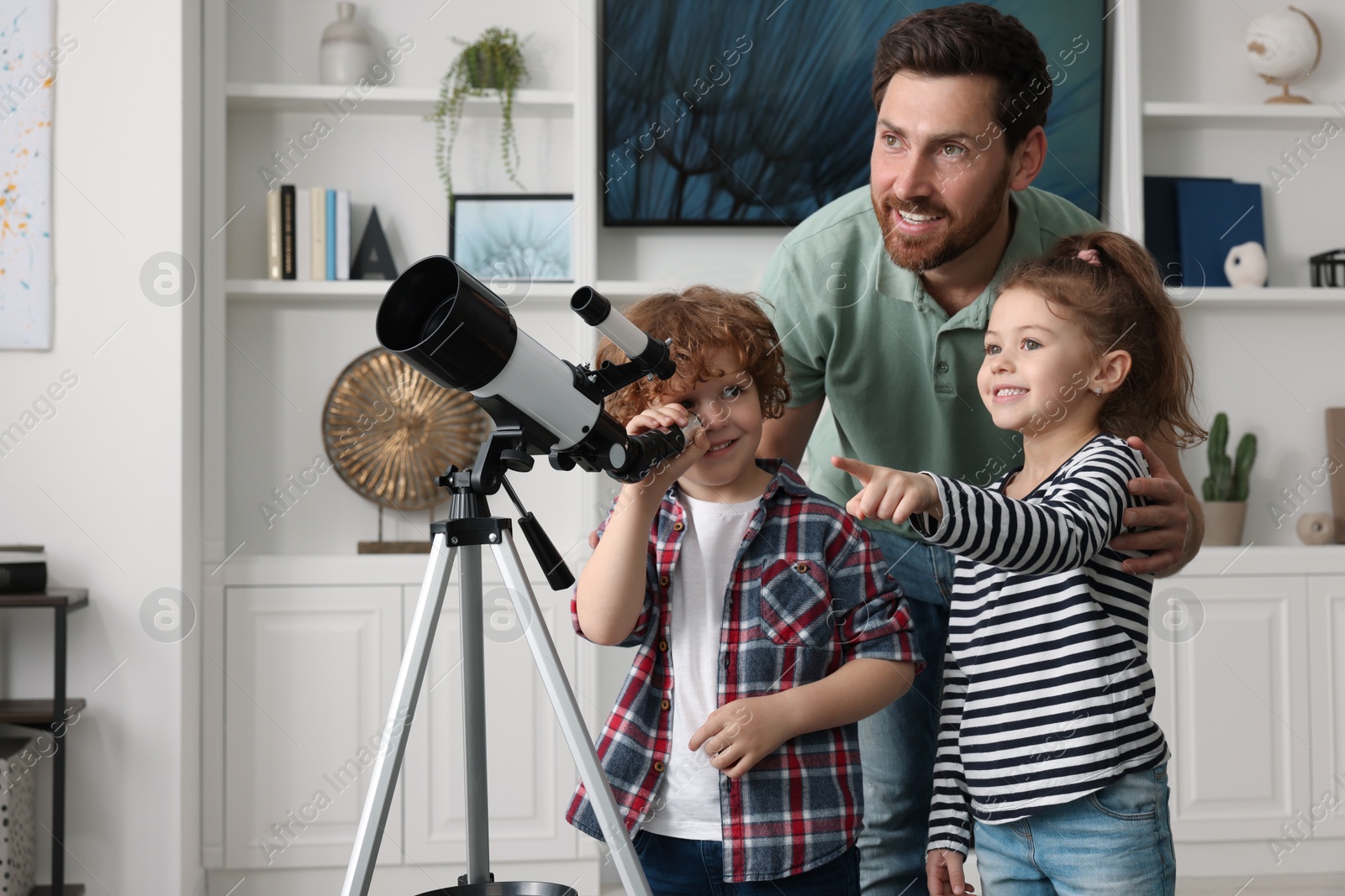 Photo of Happy father and children looking at stars through telescope in room