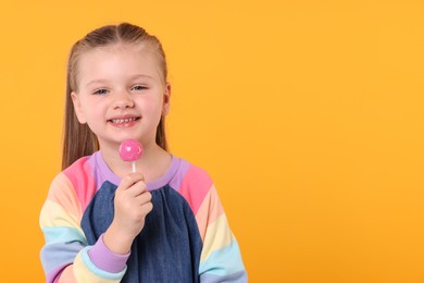 Happy little girl with lollipop on orange background, space for text