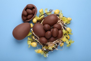 Photo of Delicious chocolate eggs on light blue background, flat lay