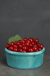 Photo of Ripe red currants in bowl on textured table. Space for text