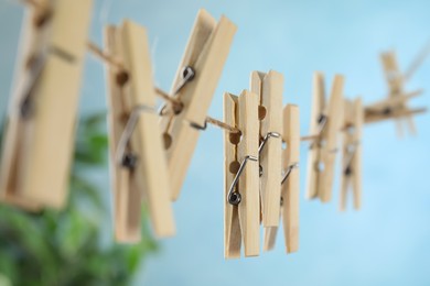 Photo of Wooden clothespins hanging on washing line against blurred background, closeup