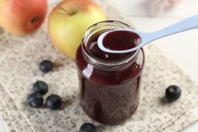 Photo of Eating baby food with spoon at white table, closeup