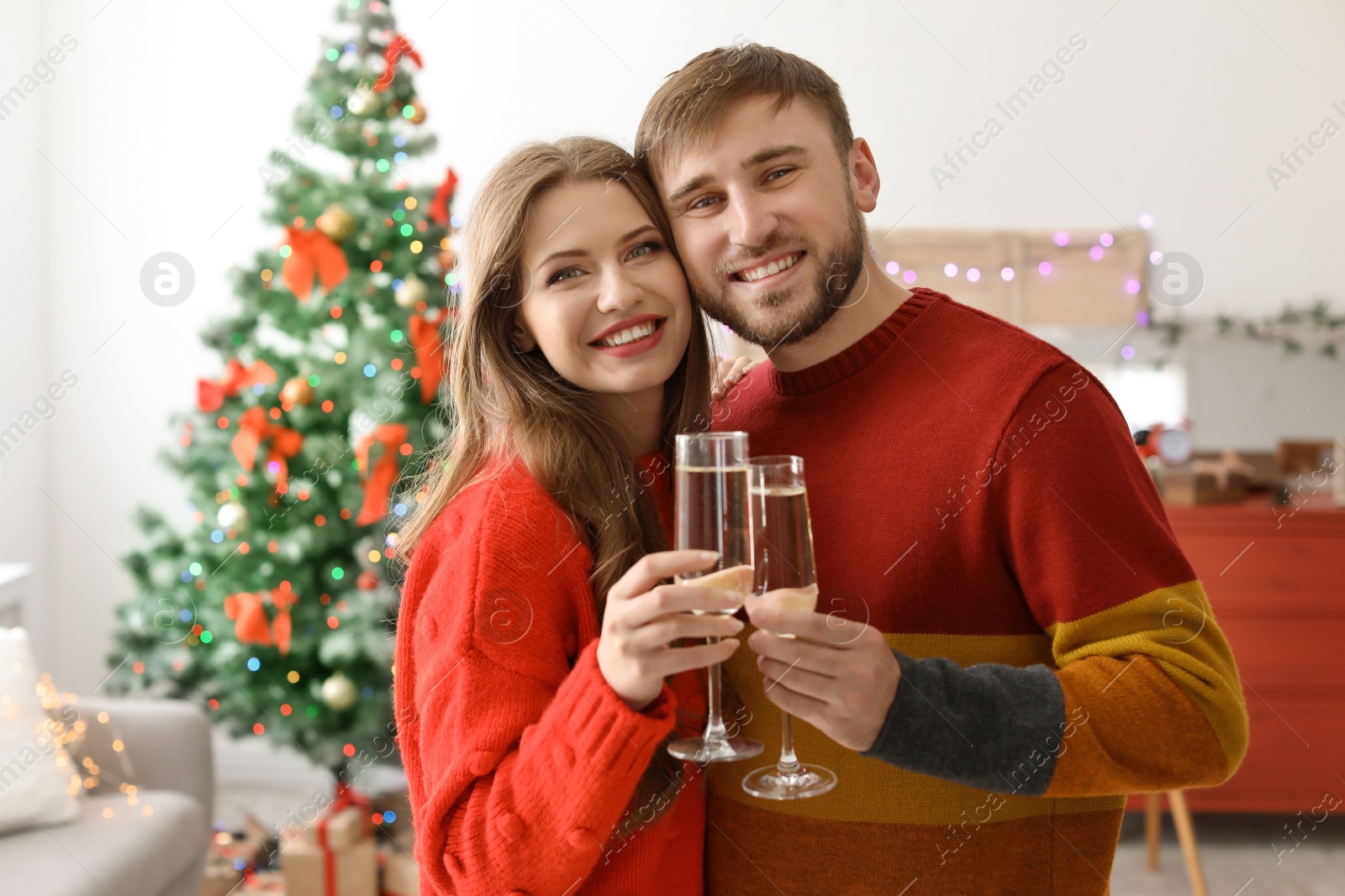 Photo of Happy young couple with glasses of champagne celebrating Christmas at home