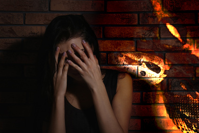 Image of Scared young woman suffering from herpetophobia near brick wall. Fear or aversion to reptiles