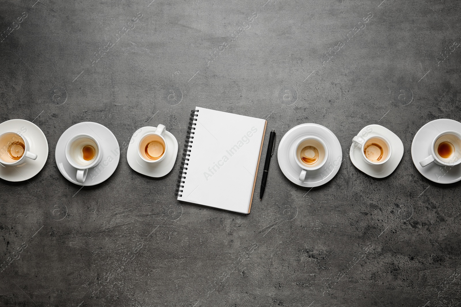 Photo of Flat lay composition with empty cups and blank notebook on grey table