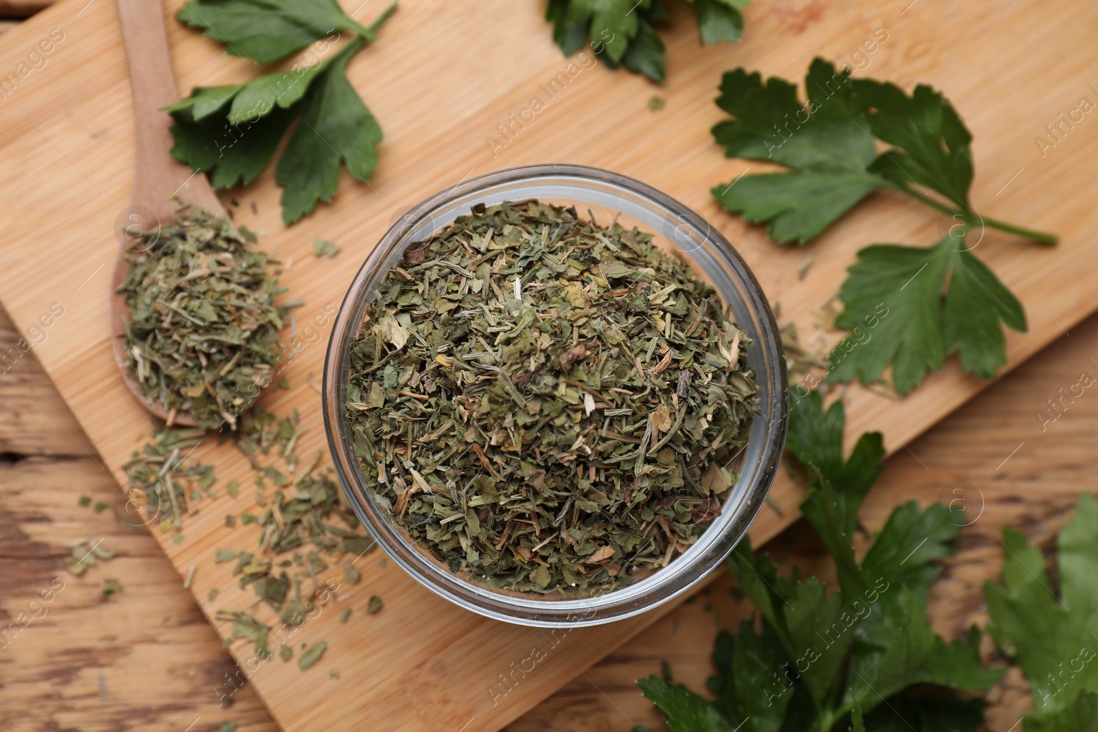 Photo of Dried parsley and fresh leaves on wooden table, flat lay
