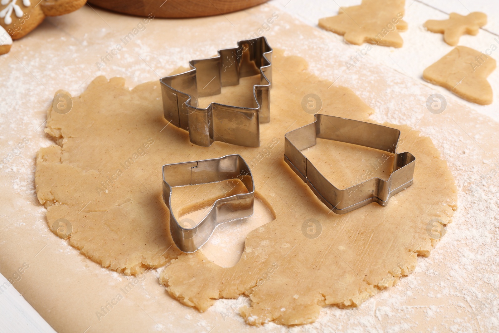 Photo of Raw dough and cookie cutters in shape of Christmas elements on table