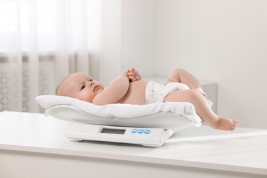 Photo of Cute little baby lying on scales in clinic